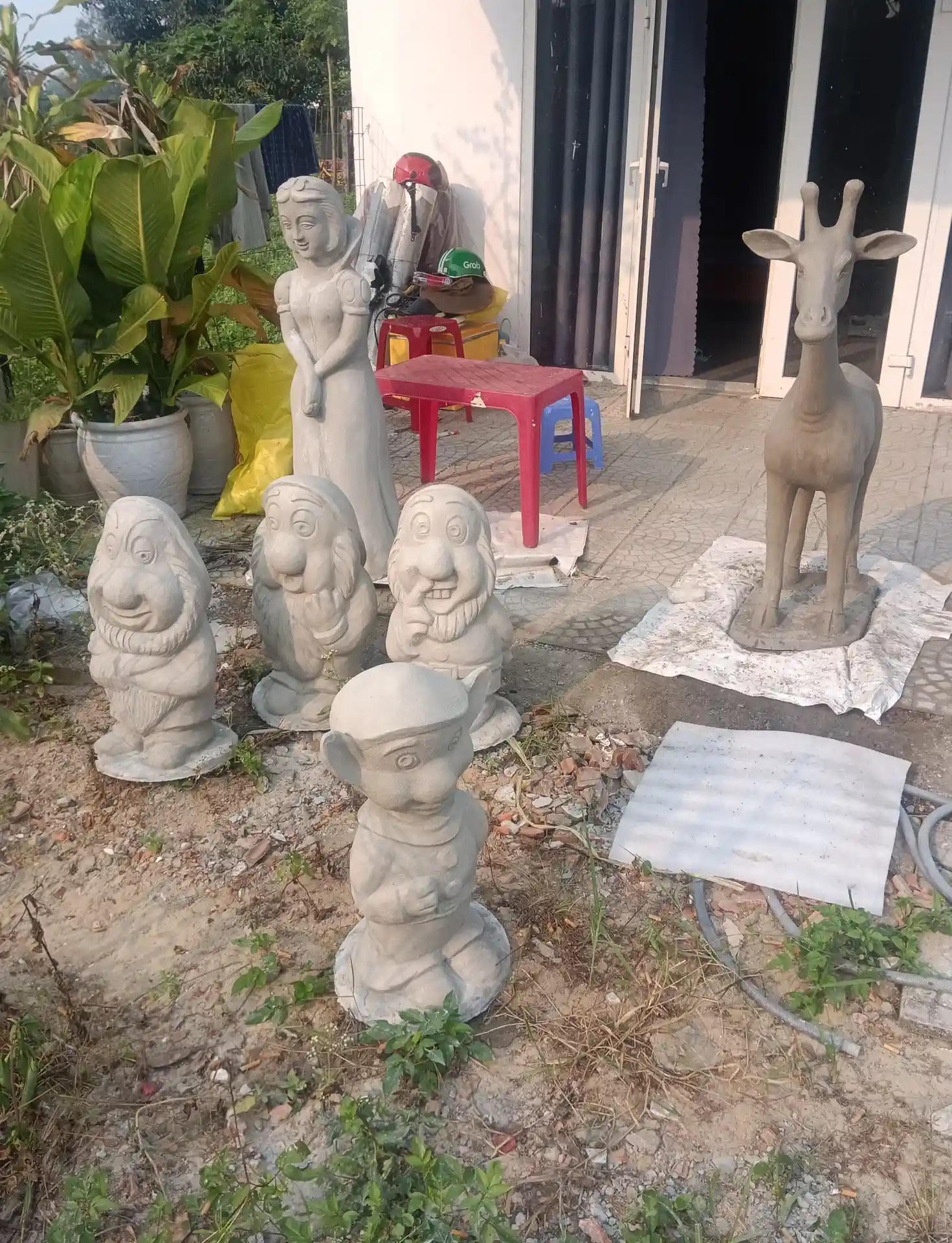 Tượng Bạch Tuyết dạng thô bằng xi măng trước khi sơn hoàn thiện, đặt cạnh tượng hươu cao cổ tại xưởng